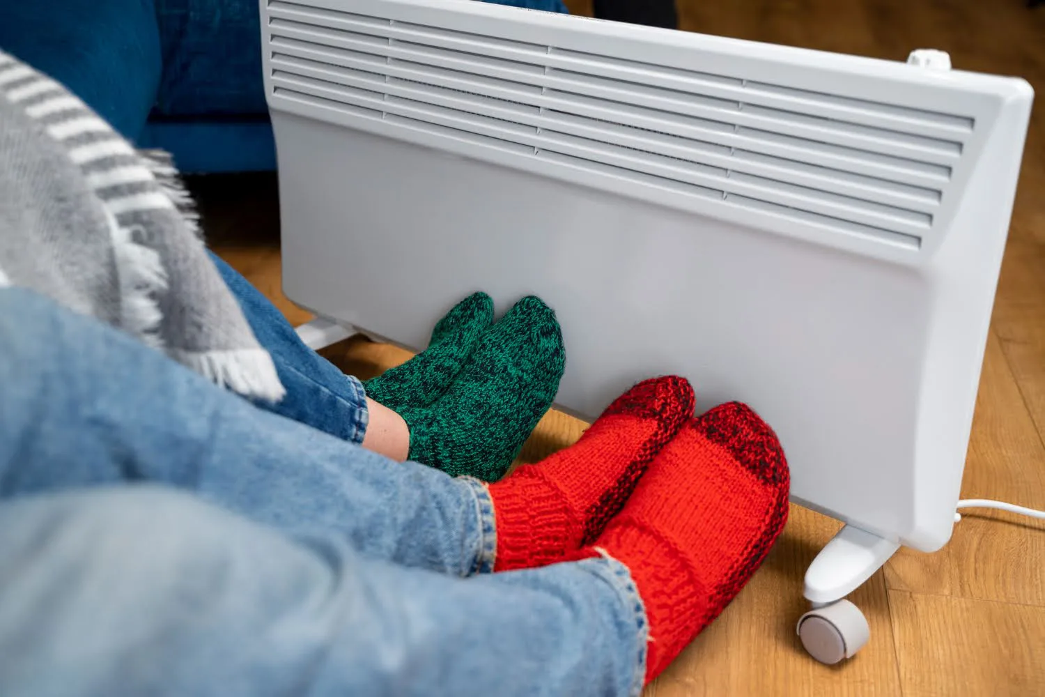 Couple staying warm in front of their heater. Featured image for “7 Common HVAC Problems During Winter”