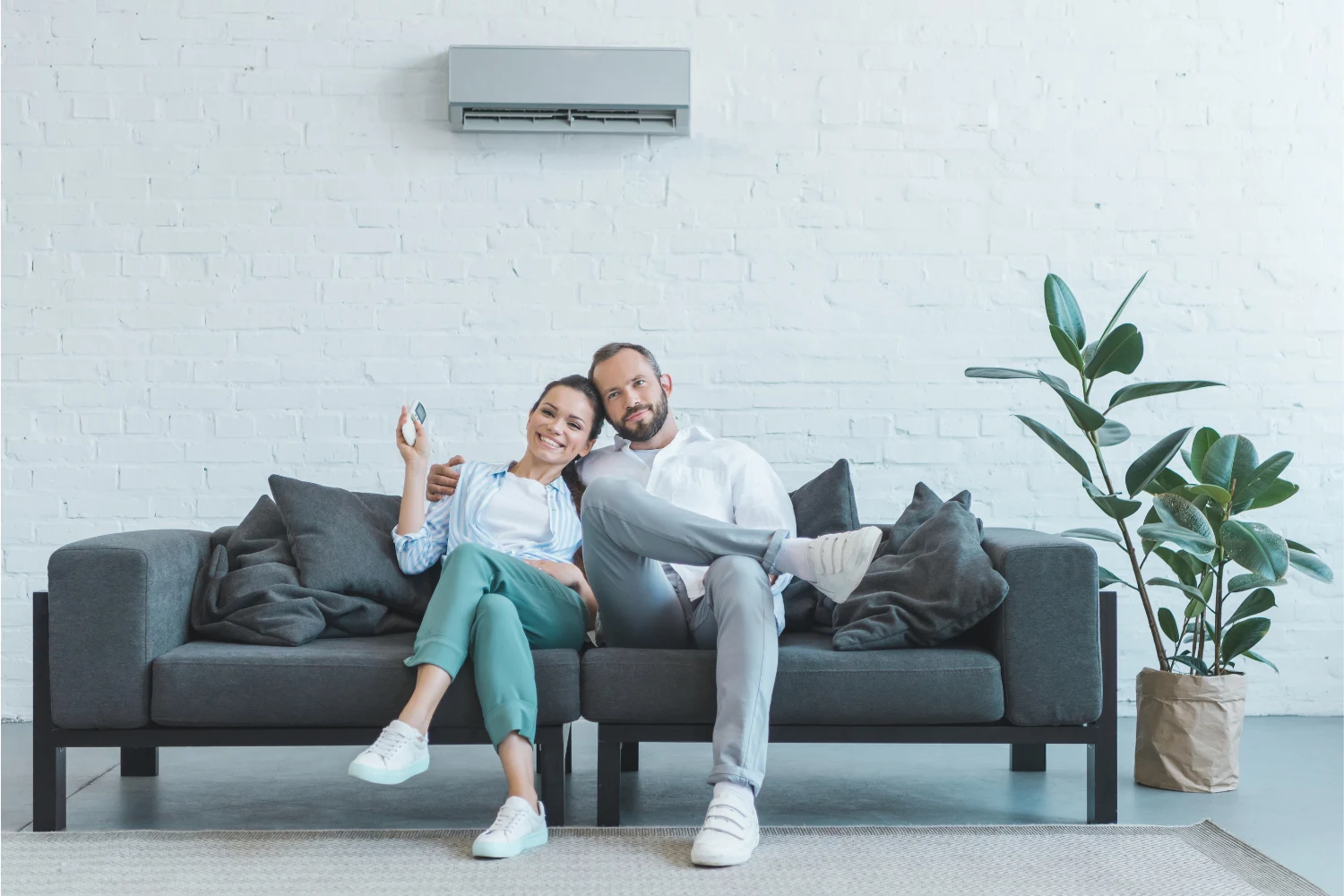Couple chilling in a living room with an air conditioner. Featured image for “8 Surprisingly Cool Air Conditioner Facts You Should Know”.